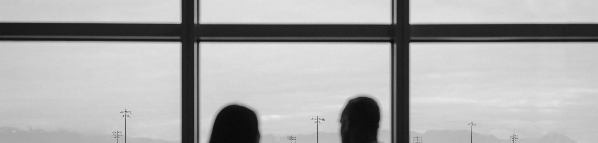 black and white photo of a couple sharing a drink at the lounge while looking out over the airport