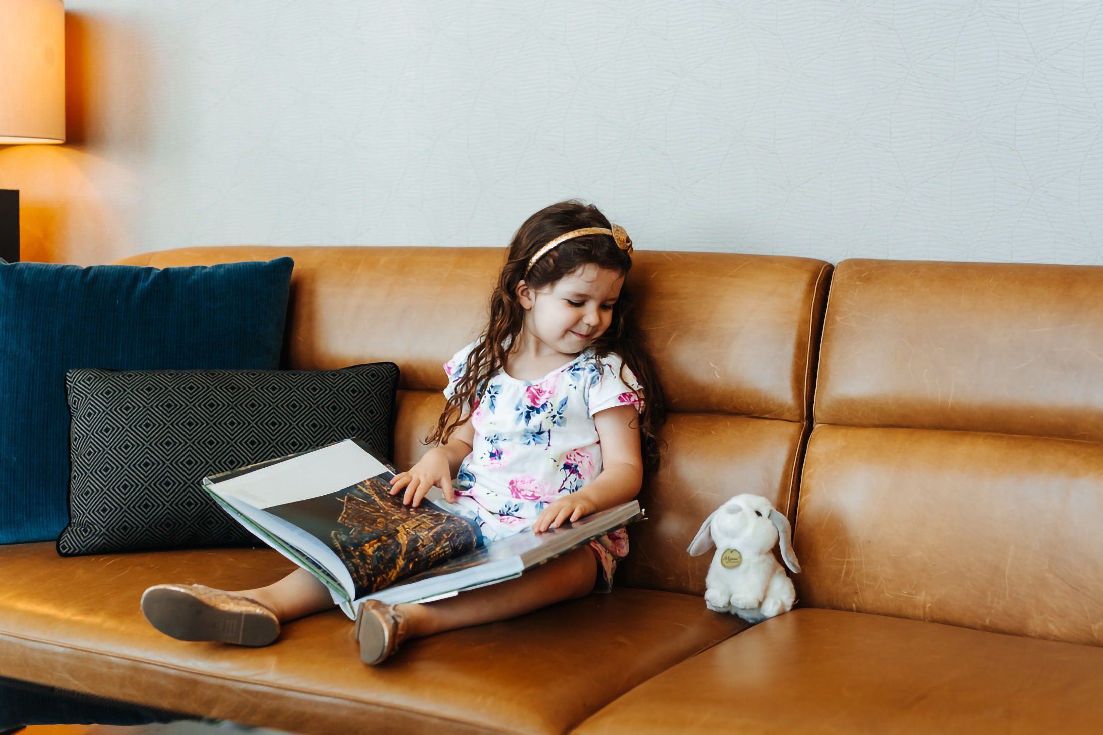 a little girl reading a book and staring at a stuffed bunny