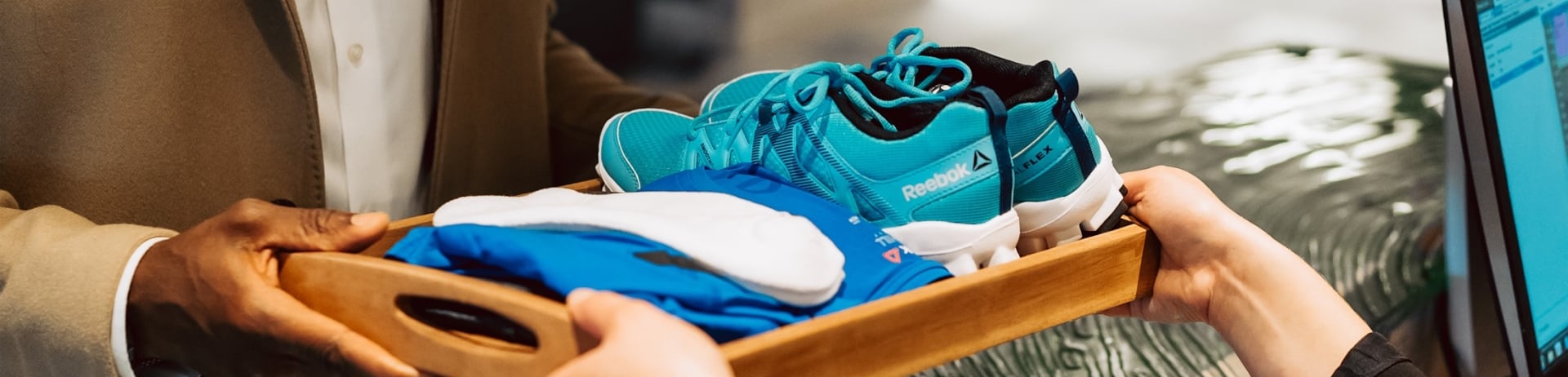 woman handing a tray of workout clothes to a man