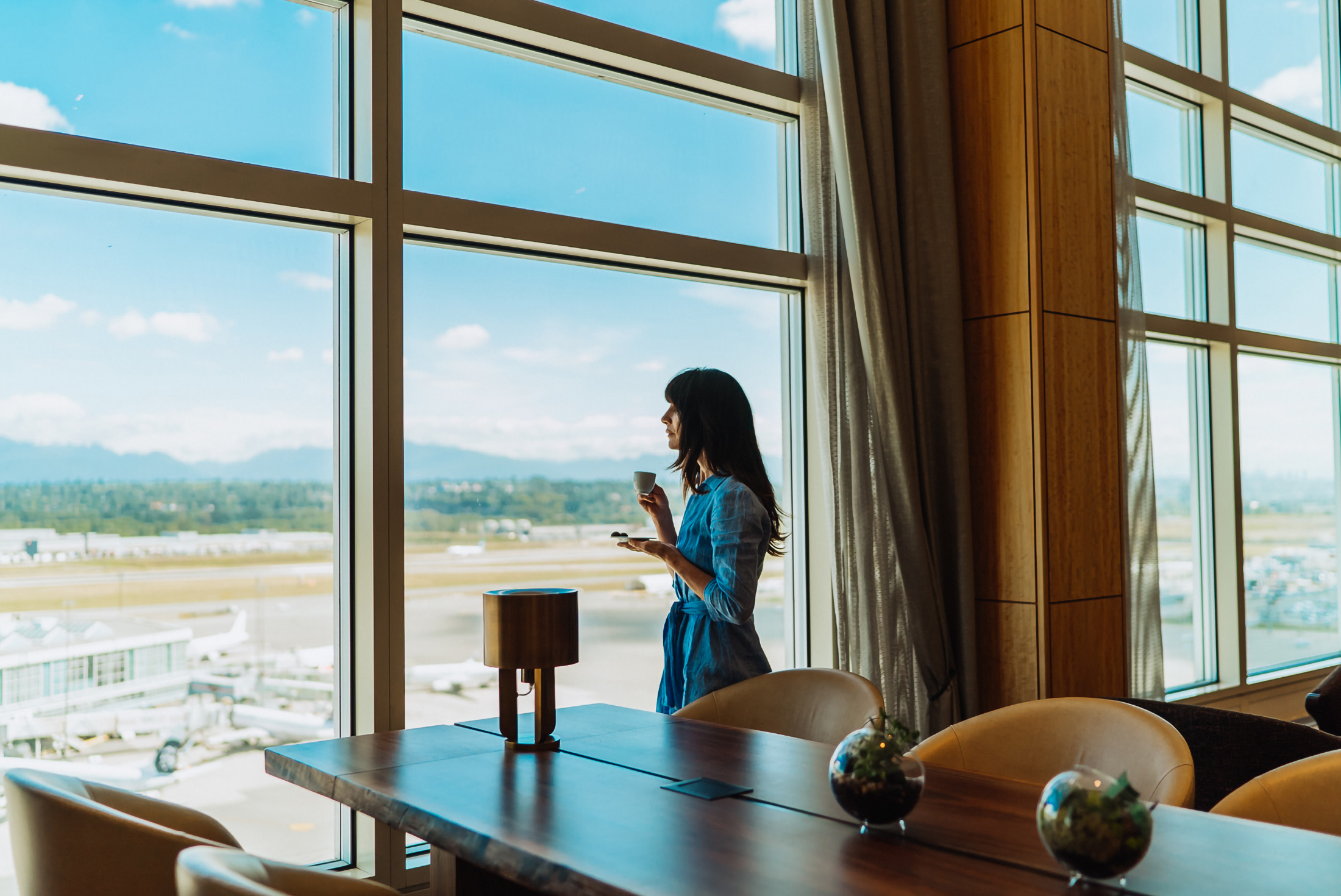 woman drinking espresso while looking out over the tarmac