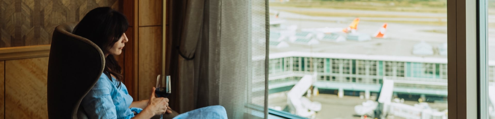 woman drinking wine while looking out at the airport