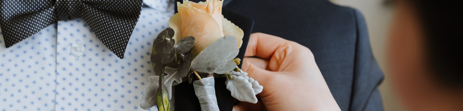 woman helping a man put on his boutonniere