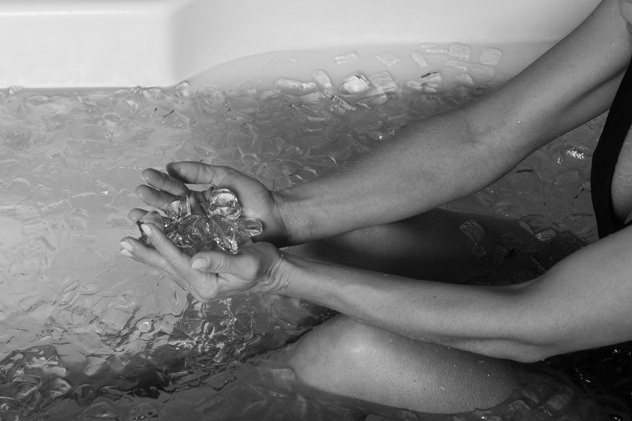 black and white photo of a woman in an ice bath holding ice