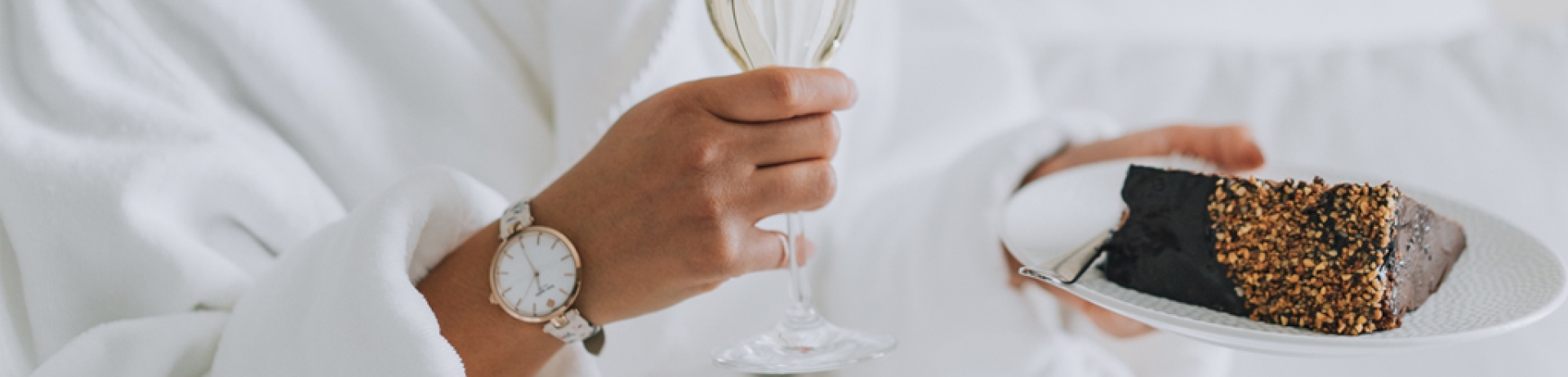 woman eating cake in bed with a glass of champagne
