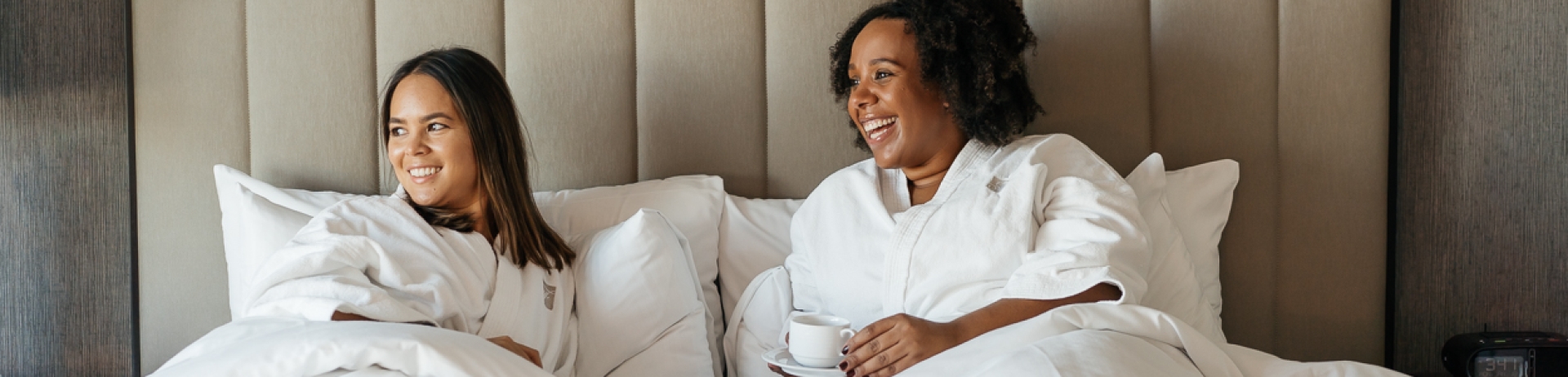 a relaxed guest looks out floor-to-ceiling windows of hotel room at airplanes landing and taking off
