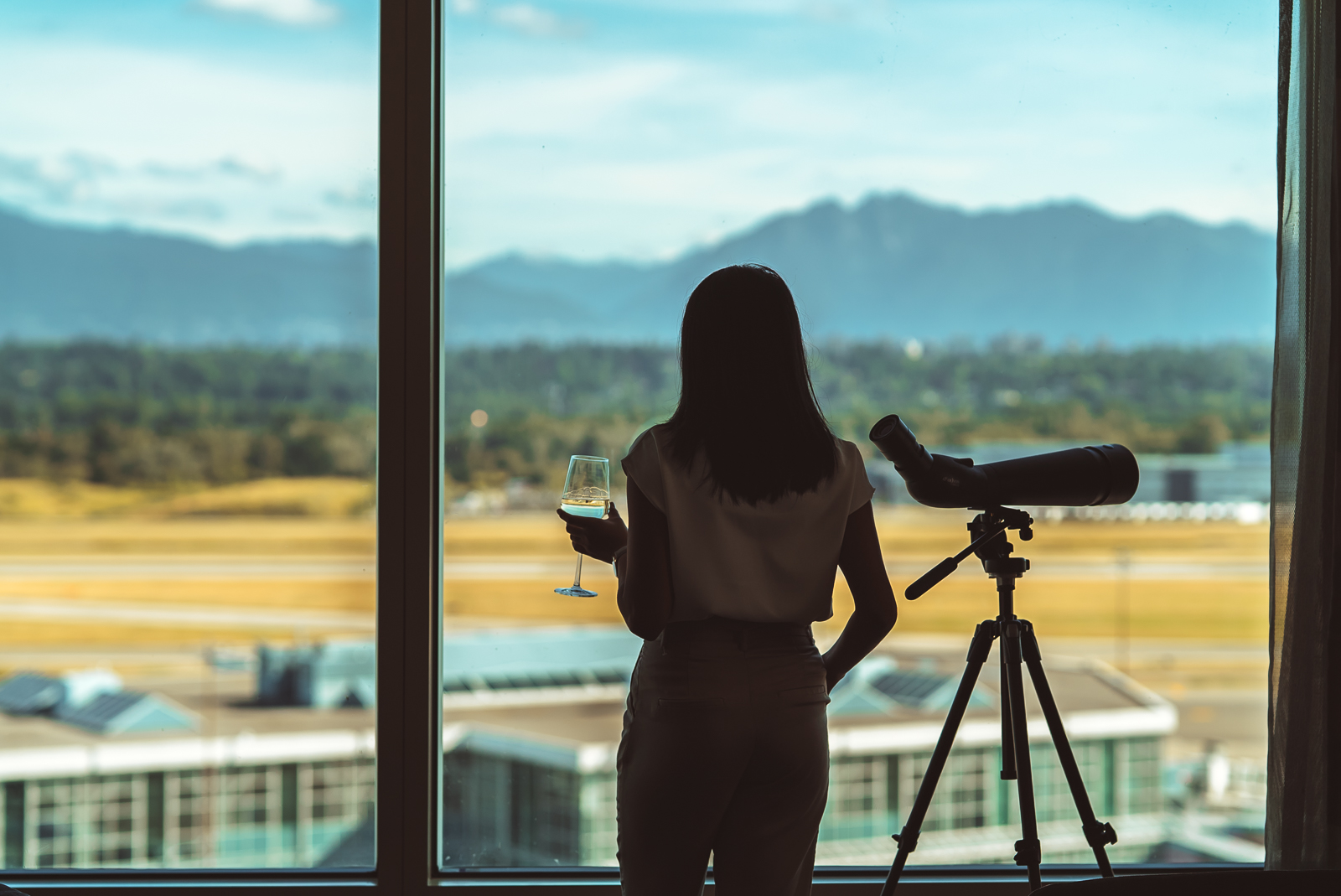 Woman enjoying the view with a telescope and a glass of wine