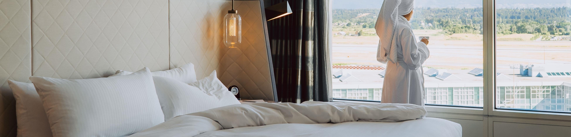 relaxed hotel guest looks our rooms floor-to-ceiling windows at airplanes landing and taking off