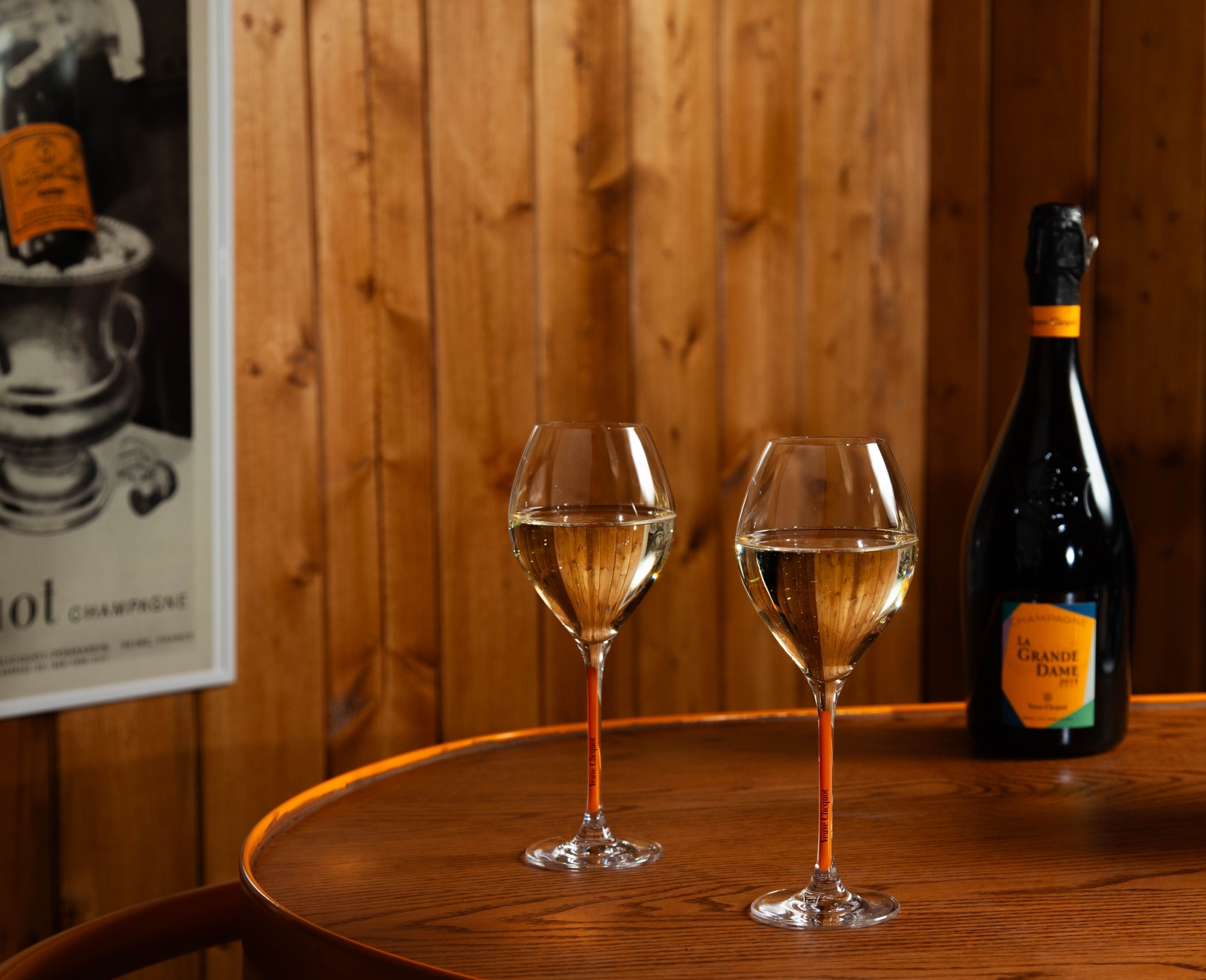 Two glasses of Veuve Clicquot Champagne with a chalet-style background