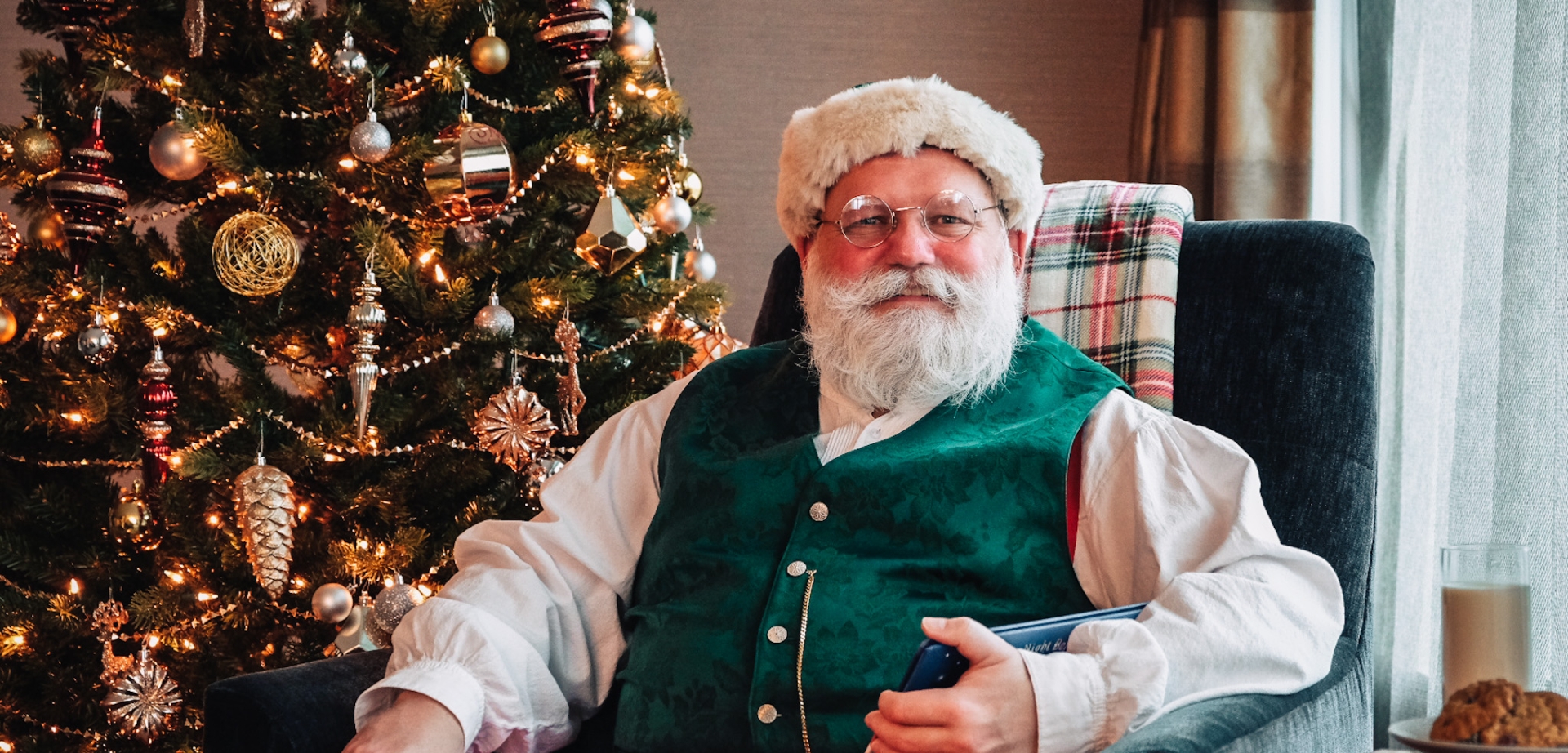 Santa sitting in a chair in front of a Christmas tree